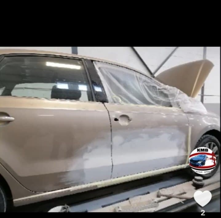 Beige hatchback with panel repairs in the booth