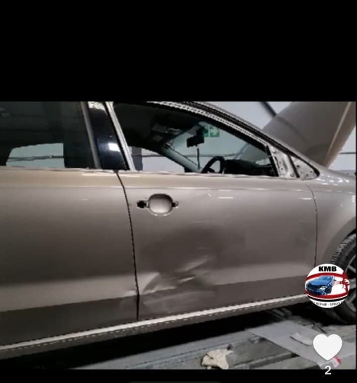 Beige sedan up on the lift for panel repair