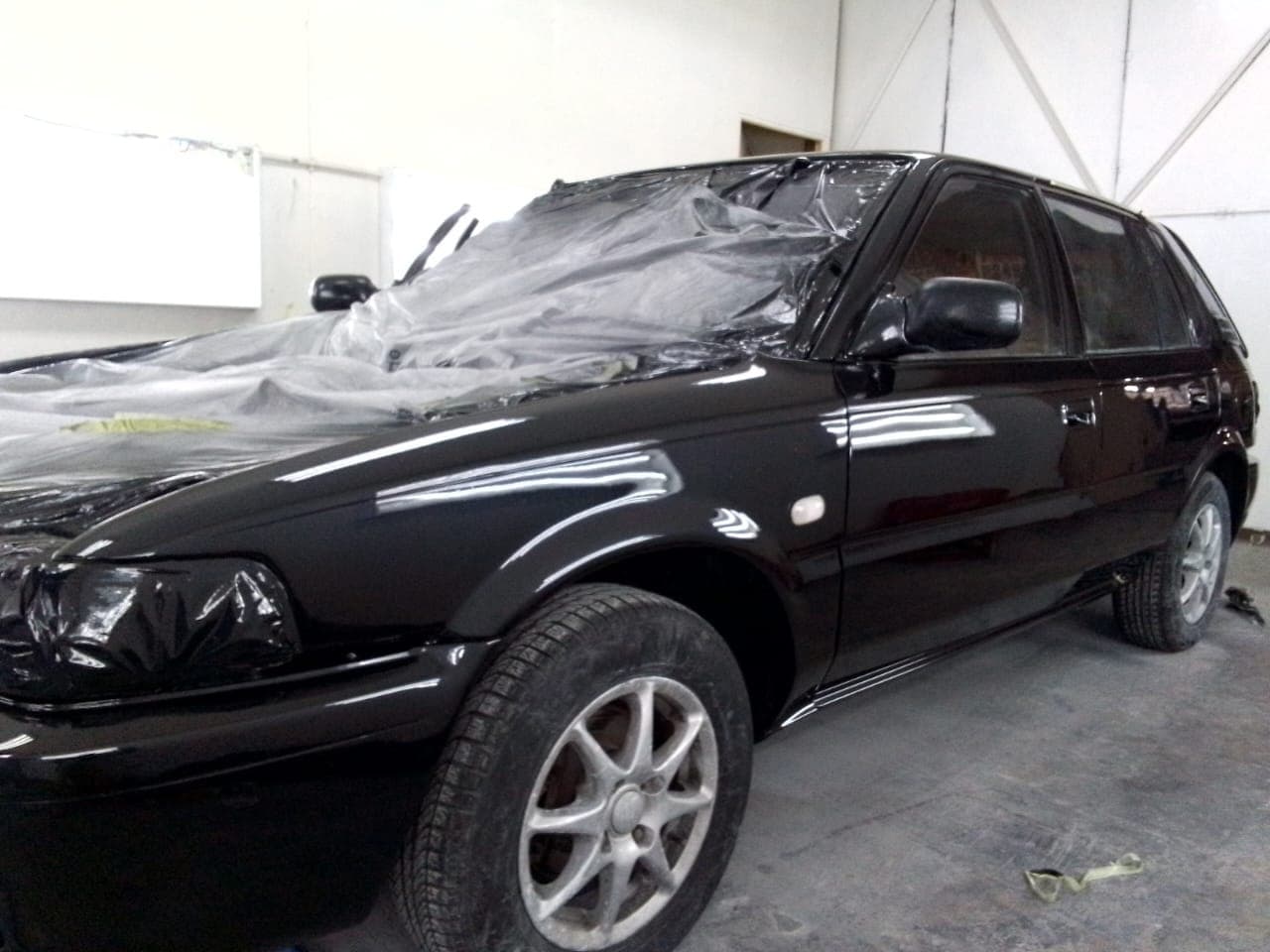 Black hatchback with a fresh, glossy respray in the booth